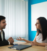 Serious businesswoman and businessman talking in boardroom. Young Caucasian woman asking male partner about their cooperation. Meeting and partnership concept